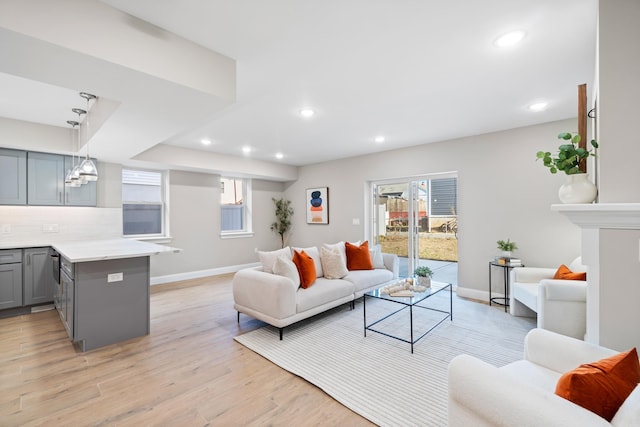 living area with recessed lighting, a healthy amount of sunlight, light wood-style flooring, and baseboards