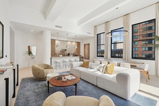 living room featuring beam ceiling, visible vents, and light wood-style flooring