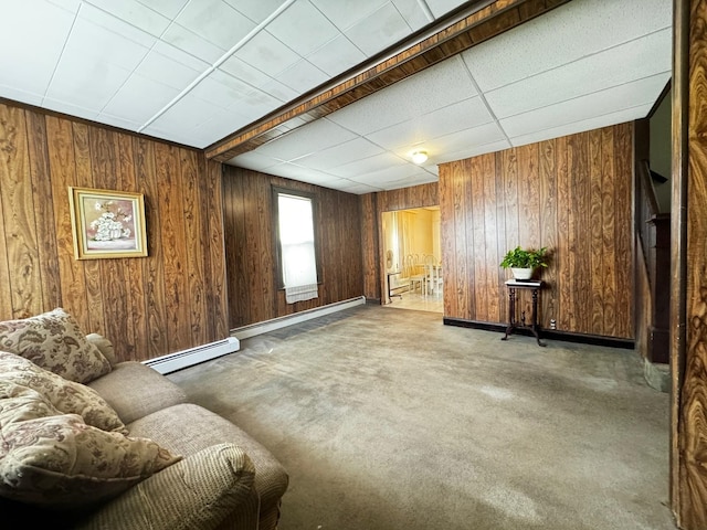 sitting room with carpet floors, baseboard heating, and wooden walls