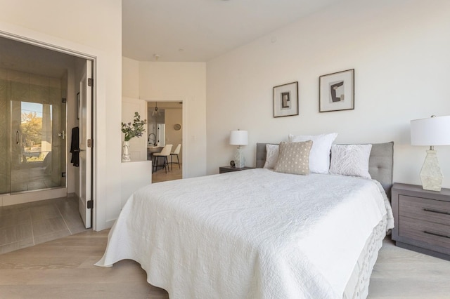 bedroom with light wood finished floors and ensuite bathroom