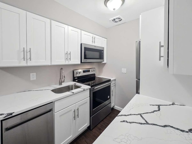 kitchen featuring stainless steel appliances, light stone counters, sink, dark hardwood / wood-style floors, and white cabinetry