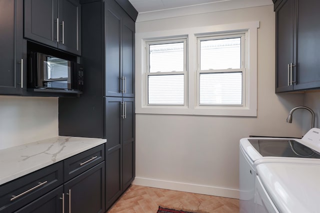 laundry room featuring washing machine and clothes dryer, light parquet floors, and cabinets