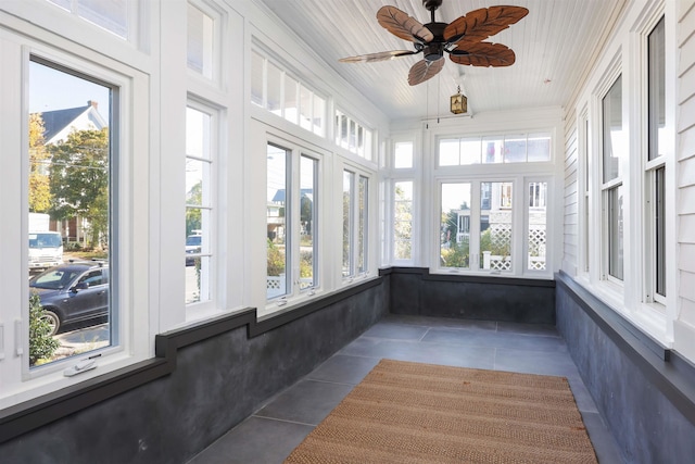 unfurnished sunroom with ceiling fan, a wealth of natural light, and wood ceiling