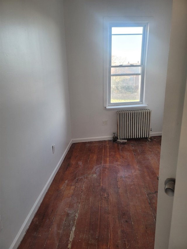 empty room with dark hardwood / wood-style floors and radiator