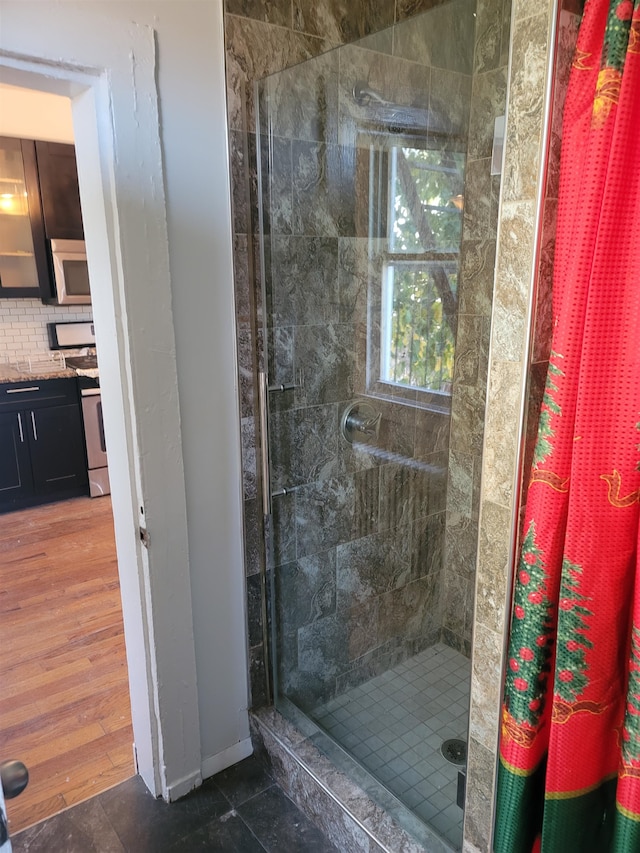 bathroom with wood-type flooring and tiled shower