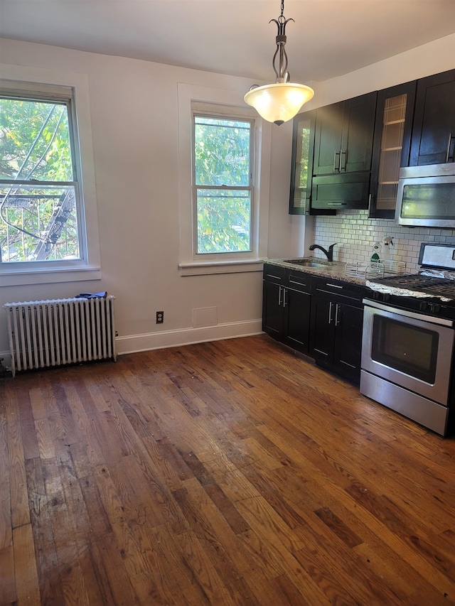 kitchen with light stone countertops, dark hardwood / wood-style flooring, radiator, stainless steel appliances, and hanging light fixtures