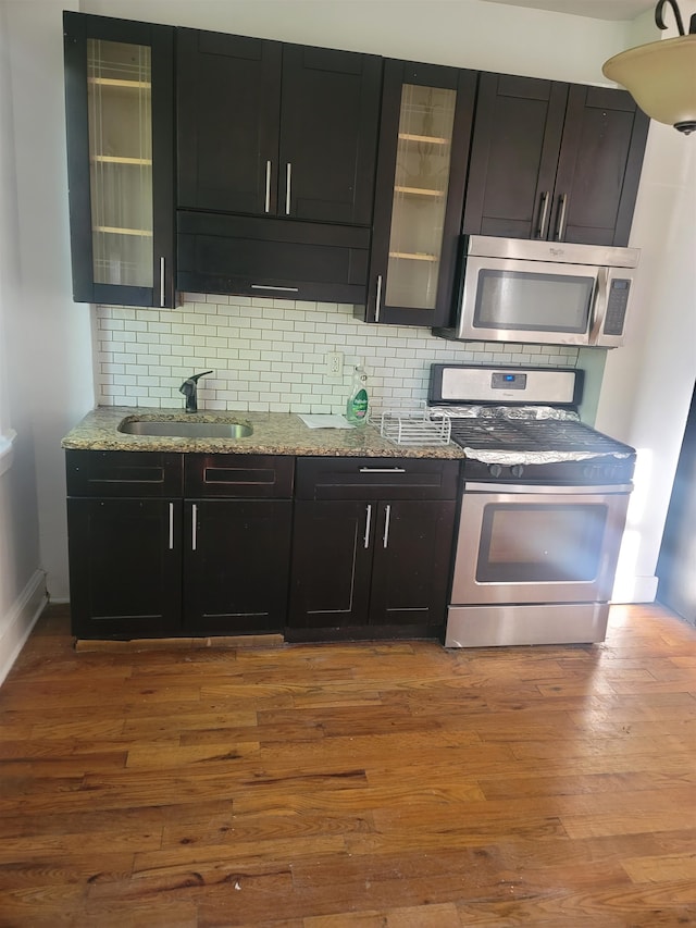 kitchen with sink, wood-type flooring, stainless steel appliances, and tasteful backsplash