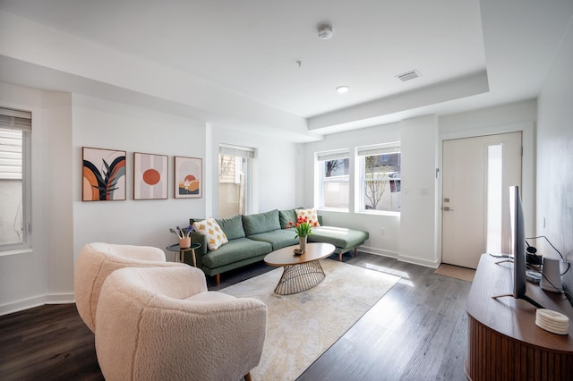 living room featuring visible vents, baseboards, and wood finished floors