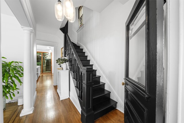 staircase with wood-type flooring and ornate columns