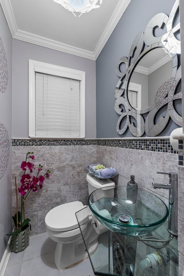 bathroom featuring tile patterned floors, toilet, ornamental molding, tile walls, and wainscoting