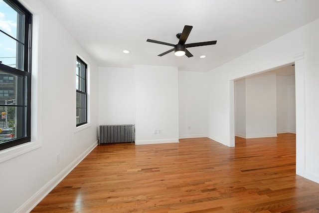 unfurnished room featuring radiator, ceiling fan, and light hardwood / wood-style flooring