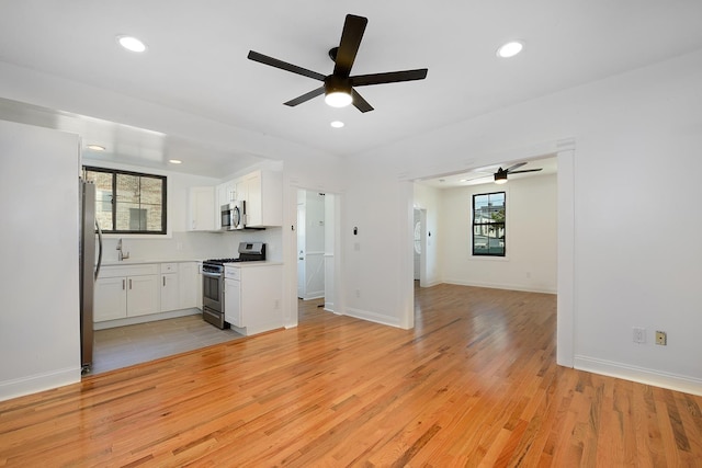 kitchen featuring appliances with stainless steel finishes, white cabinets, light hardwood / wood-style floors, and decorative backsplash