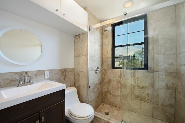 bathroom with tile walls, vanity, toilet, and a tile shower