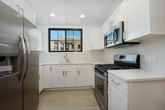 kitchen featuring appliances with stainless steel finishes, sink, white cabinets, and decorative backsplash