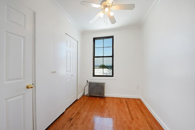 spare room with ornamental molding, radiator, ceiling fan, and light wood-type flooring