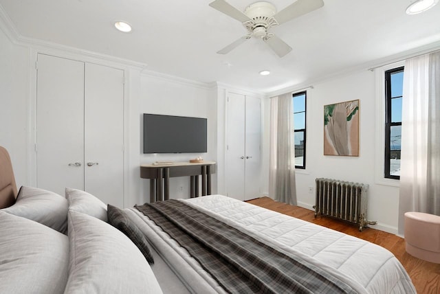 bedroom featuring multiple windows, radiator, wood-type flooring, and ceiling fan