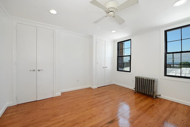 unfurnished bedroom with ornamental molding, radiator heating unit, ceiling fan, and light hardwood / wood-style floors