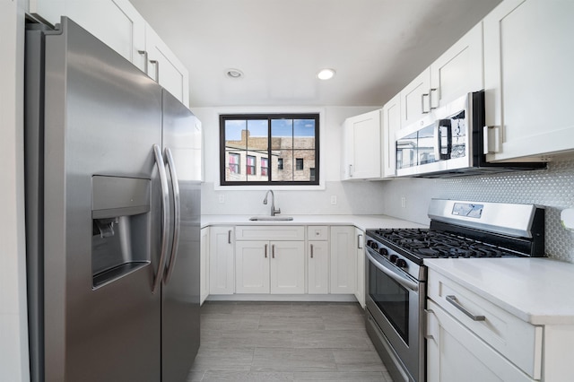 kitchen featuring stainless steel appliances, white cabinetry, sink, and tasteful backsplash