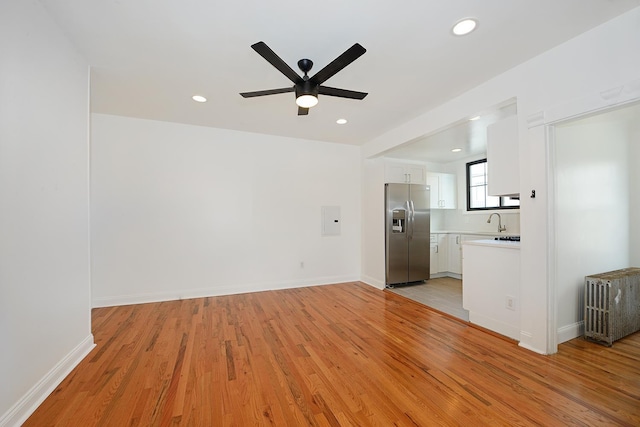 unfurnished living room featuring ceiling fan, sink, and light wood-type flooring