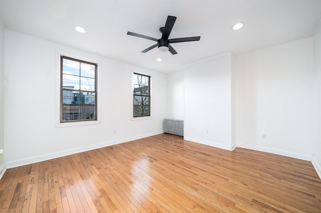 spare room with ceiling fan, radiator, and light hardwood / wood-style flooring