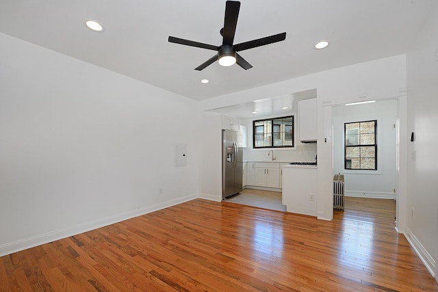 unfurnished living room featuring sink, a wealth of natural light, light hardwood / wood-style floors, and ceiling fan