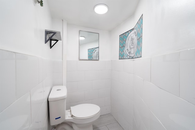 bathroom featuring toilet and tile walls