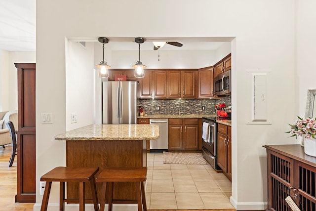 264 9th St Unit 3C, Jersey City, NJ 07302 - kitchen featuring stainless steel appliances, decorative backsplash, a ceiling fan, light stone countertops, and a breakfast bar area