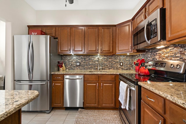 264 9th St Unit 3C, Jersey City, NJ 07302 - kitchen featuring appliances with stainless steel finishes, decorative backsplash, light tile patterned flooring, ceiling fan, and light stone counters