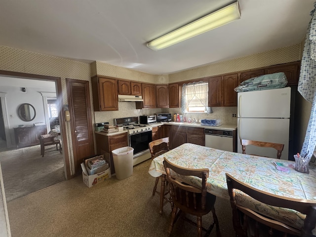 kitchen featuring white appliances, wallpapered walls, light countertops, carpet floors, and under cabinet range hood