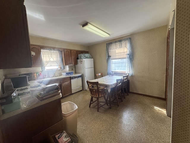 kitchen with wallpapered walls, light countertops, dishwasher, and freestanding refrigerator