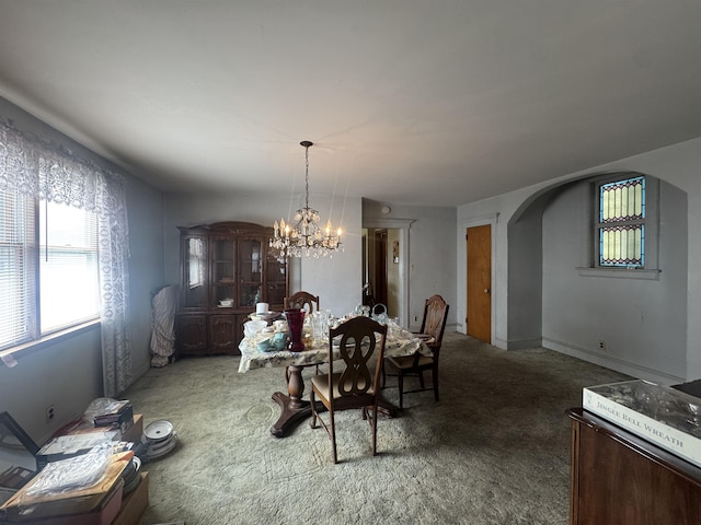 dining space with arched walkways, a chandelier, and carpet flooring