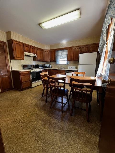 40 E 31st St, Bayonne, NJ 07002 - kitchen with white appliances, under cabinet range hood, light countertops, and brown cabinets