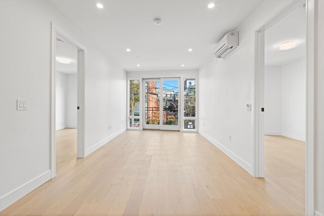 391 1st St Unit 2-C, Jersey City, NJ 07302 - empty room featuring a wall mounted air conditioner, light wood-style flooring, baseboards, recessed lighting, and a smoke detector