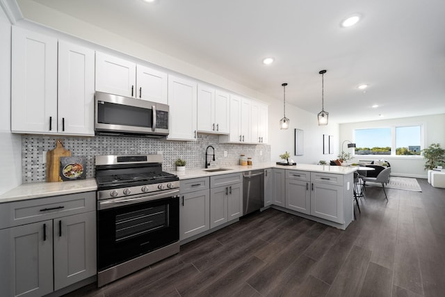 kitchen featuring sink, kitchen peninsula, appliances with stainless steel finishes, gray cabinetry, and dark hardwood / wood-style flooring