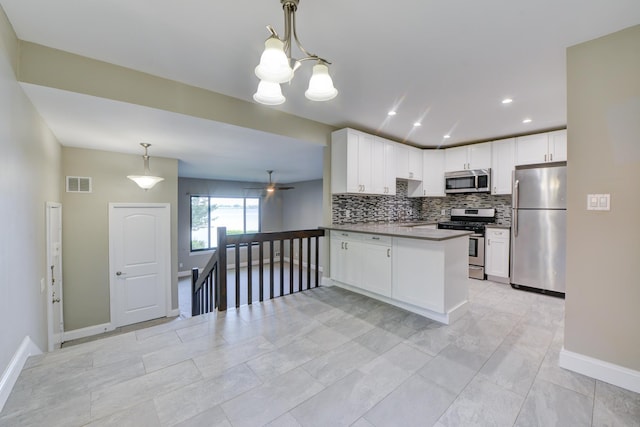 98 Sandpiper Ky, Secaucus, NJ 07094 - kitchen featuring stainless steel appliances, tasteful backsplash, a peninsula, white cabinets, and hanging light fixtures