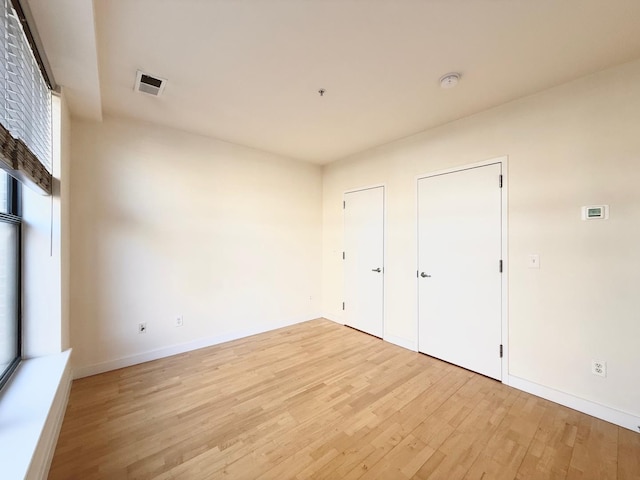 unfurnished bedroom with light wood-style floors, visible vents, and baseboards