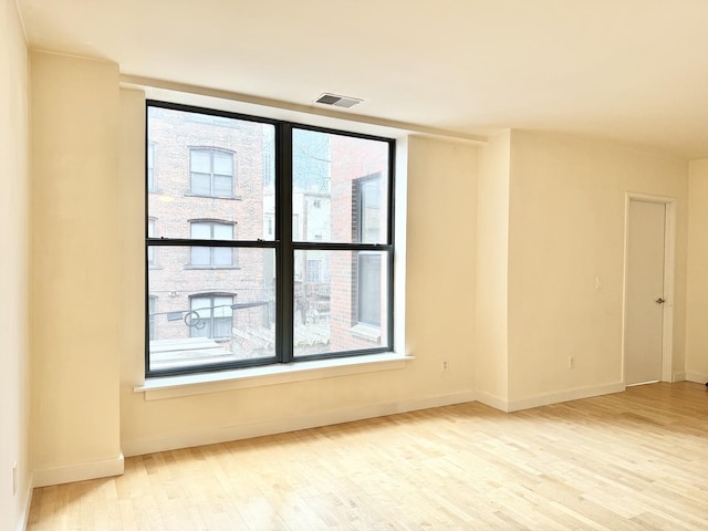 spare room with visible vents, baseboards, and wood finished floors