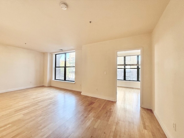 unfurnished room featuring a wealth of natural light, baseboards, and light wood-style floors