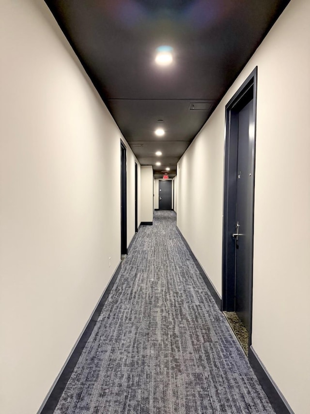 hall featuring recessed lighting, dark carpet, and baseboards