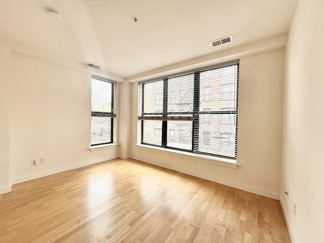 unfurnished room with visible vents, baseboards, and wood finished floors