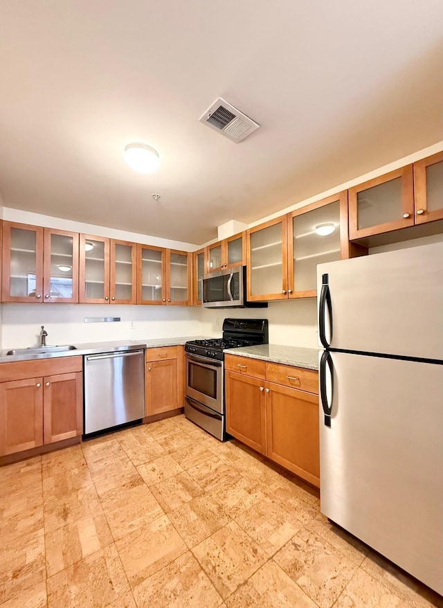 kitchen featuring a sink, stainless steel appliances, glass insert cabinets, and visible vents