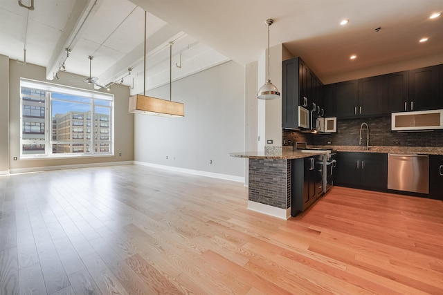 kitchen with tasteful backsplash, light stone countertops, open floor plan, light wood-type flooring, and stainless steel appliances