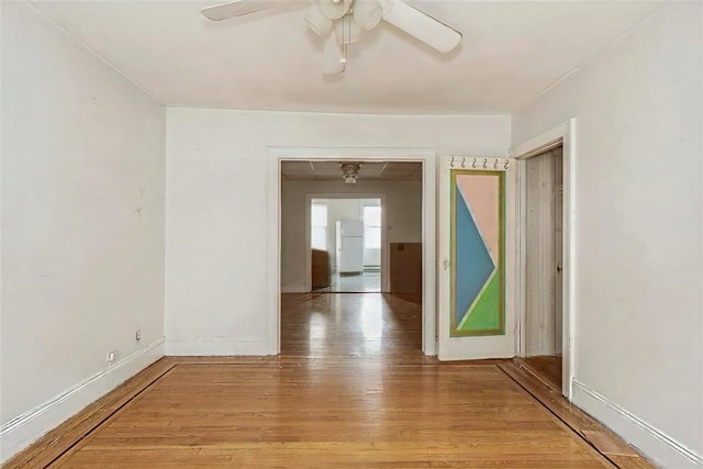 empty room with baseboards, a ceiling fan, and light wood-style floors