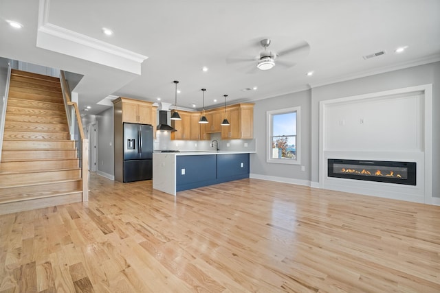 kitchen featuring pendant lighting, a center island, light brown cabinets, wall chimney exhaust hood, and fridge with ice dispenser