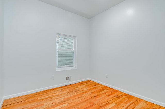 spare room featuring visible vents, baseboards, and wood finished floors