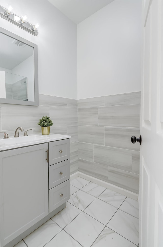 bathroom featuring vanity, visible vents, wainscoting, tile walls, and marble finish floor