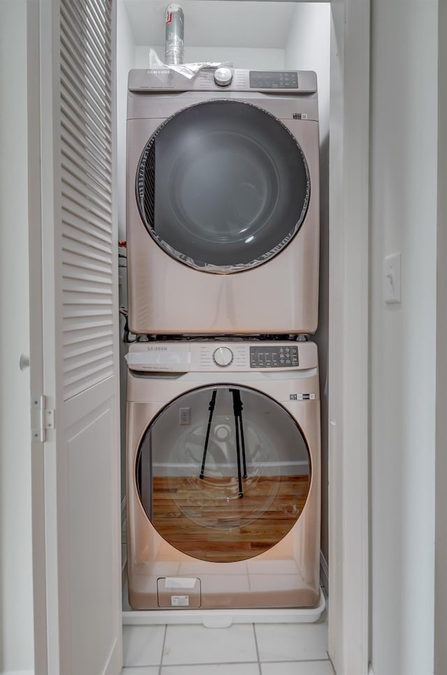 washroom featuring stacked washer and clothes dryer, laundry area, and tile patterned flooring