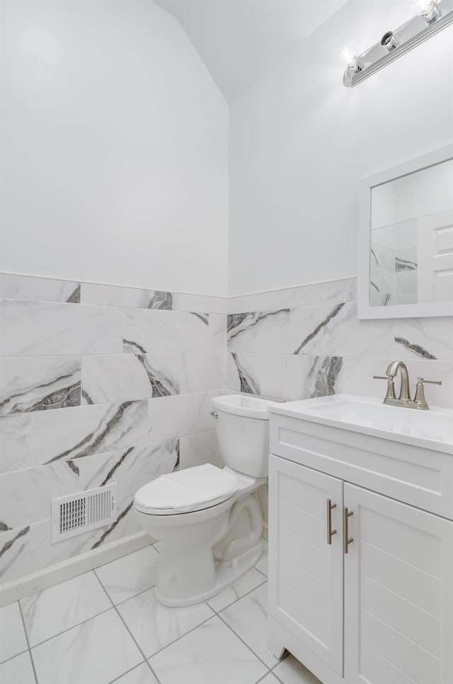 bathroom with vanity, visible vents, tile walls, toilet, and marble finish floor