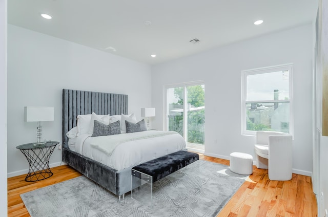 bedroom featuring access to exterior, visible vents, baseboards, and wood finished floors