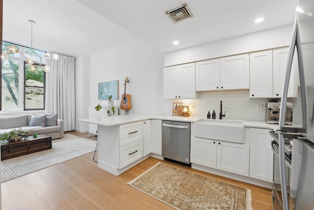 120 Sherman Ave Unit 2B, Jersey City, NJ 07307 - kitchen with appliances with stainless steel finishes, a sink, a peninsula, light countertops, and a chandelier